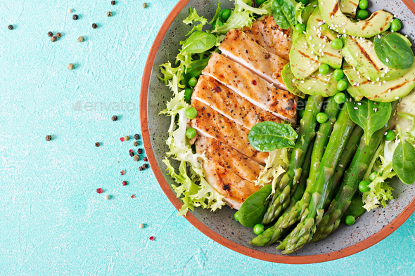 Chicken fillet cooked on a grill with a garnish of asparagus and grilled avokado - Stock Photo - Images