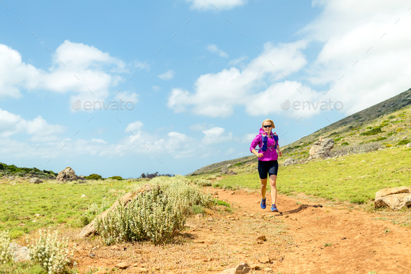 Happy woman trail running in beautiful mountains