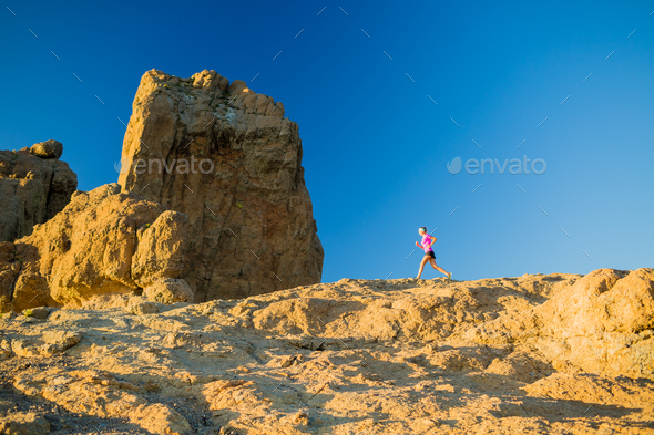 Woman running on rocky mountains, training and working out - Stock Photo - Images
