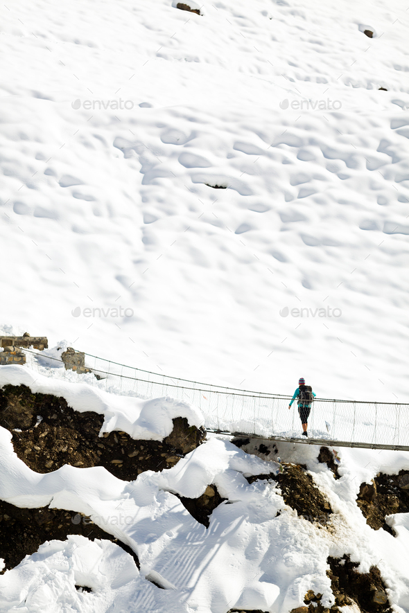 Woman walking on bridge in winter mountains - Stock Photo - Images