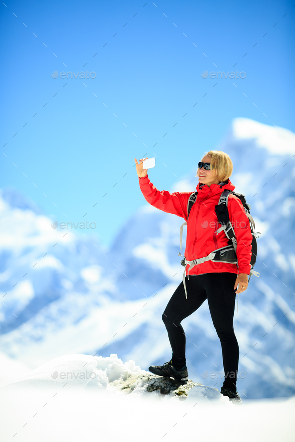 Woman doing smartphone selfie in mountains - Stock Photo - Images