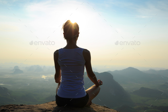 Meditation on sunrise mountain top cliff edge - Stock Photo - Images