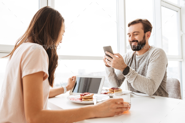 Modern young couple having breakfast while sitting together - Stock Photo - Images