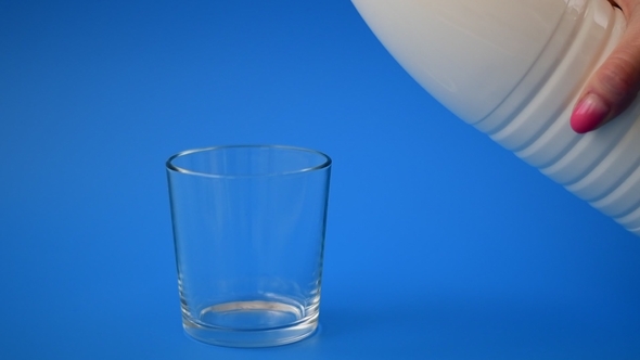 Milk Is Poured From Bottle Into the Glass in