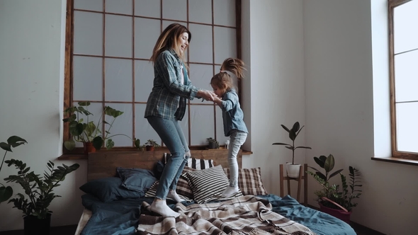 Mom And Daughter Are Having Fun Jumping Together On A Bed Stock Footage