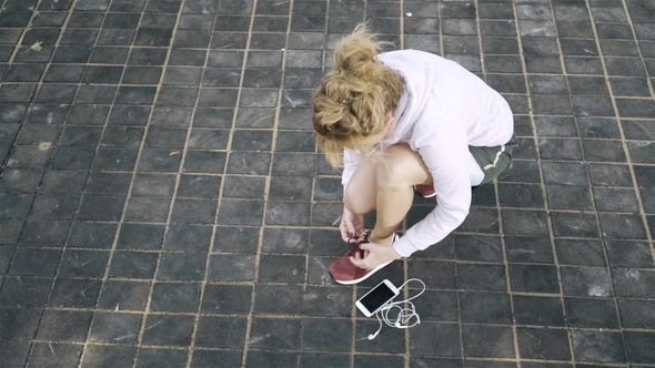 Top View of a Jogger Woman Tying Her Shoelace and Starting To Run Outside
