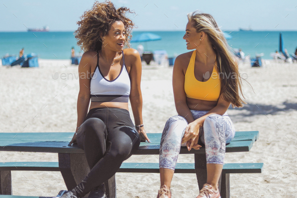 Lounging girlfriends in sportswear on beach - Stock Photo - Images