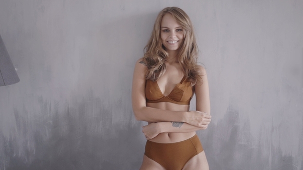 Smiling Young Woman with a Beautiful Body Against Gray Wall
