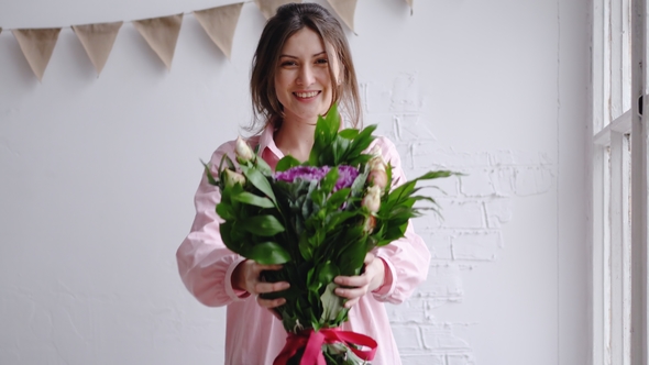 Florist Girl Looks at the Camera and Shows the Bouquet. Portrait in a Flower Shop