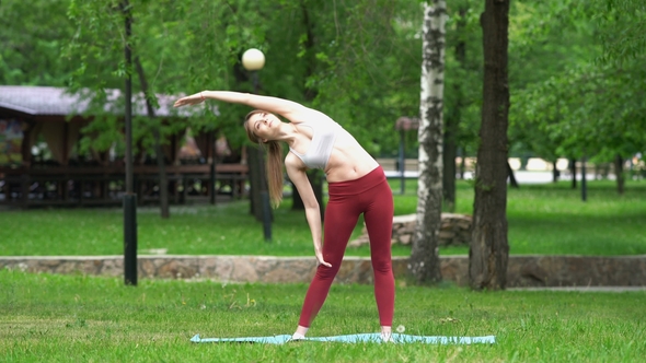 Young Beautiful Woman Doing Yoga Exercises in Park alt