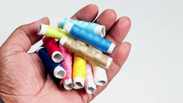 Hand Holds Colored Thread Spools Off Center