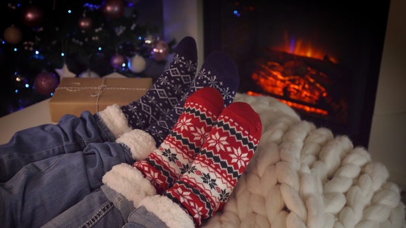 Couple Sitting in Woolen Socks near Fireplace on Christmas Holidays alt