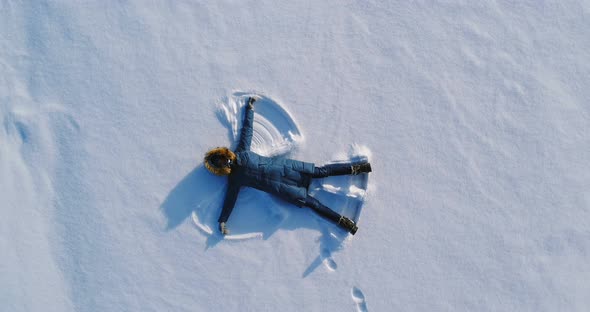 Woman Makes Snow Angel Laying in the Snow
