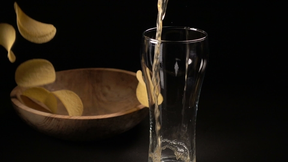 Potato Chips Are Poured Into a Wooden Bowl and Beer Is Poured Into a Glass