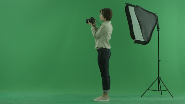 A Young Woman Taking Photos on the Left Hand Side on the Green Screen