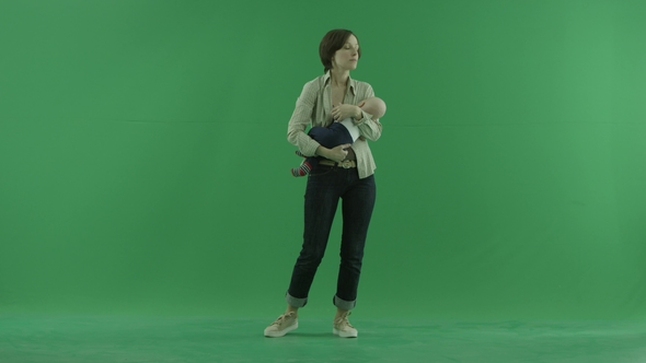 A Young Woman Rocks Her Baby on the Green Screen