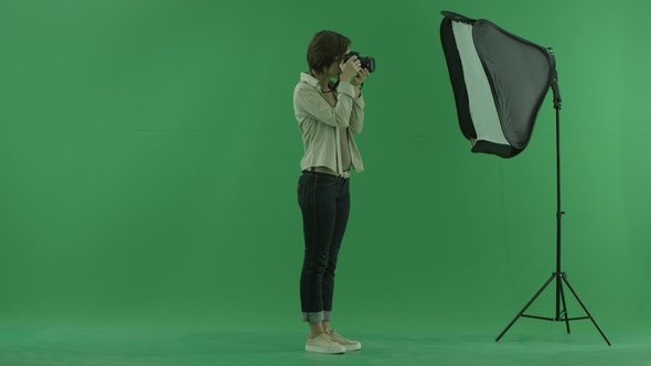 A Young Woman Taking Photos on the Right Hand Side on the Green Screen and Corrects Standing of a