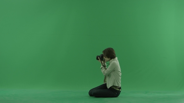 Sitting Young Woman Is Taking Photos on the Left Hand Side on the Green Screen