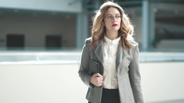 a Business Woman in a Gray Jacket Goes To the Lobby of the Business Center. Girl in a Business Suit alt