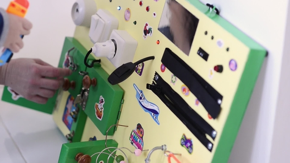 Little Baby Boy Intently Playing with Busy Board alt