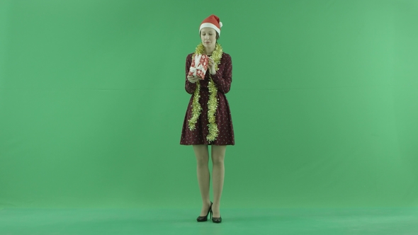 A Young Woman Is Looking for a Christmas Gift on the Green Screen