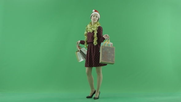 A Young Girl Is Showing Results of Christmas Shopping for the Viewer on the Green Screen