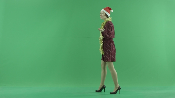 A Young Christmas Woman Is Going From the Right Side Under the Snowfall on the Green Screen