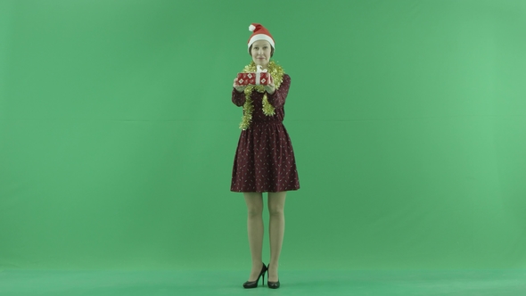 A Young Woman Is Giving a Christmas Gift for a Viewer on the Green Screen