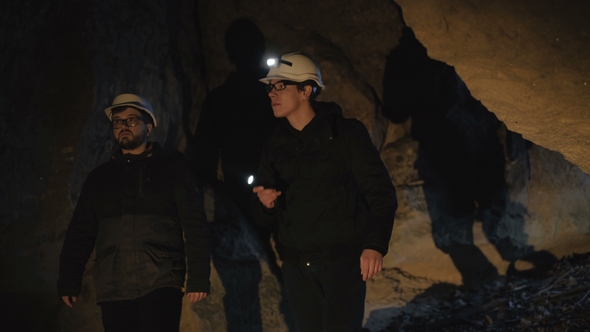 Two Speleologists with Flashlight Exploring the Cave with Fear in Darkness alt