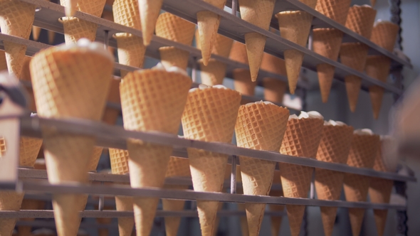 Rows of Waffle Cones Are Getting Lifted and Lowered By a Factory Mechanism alt
