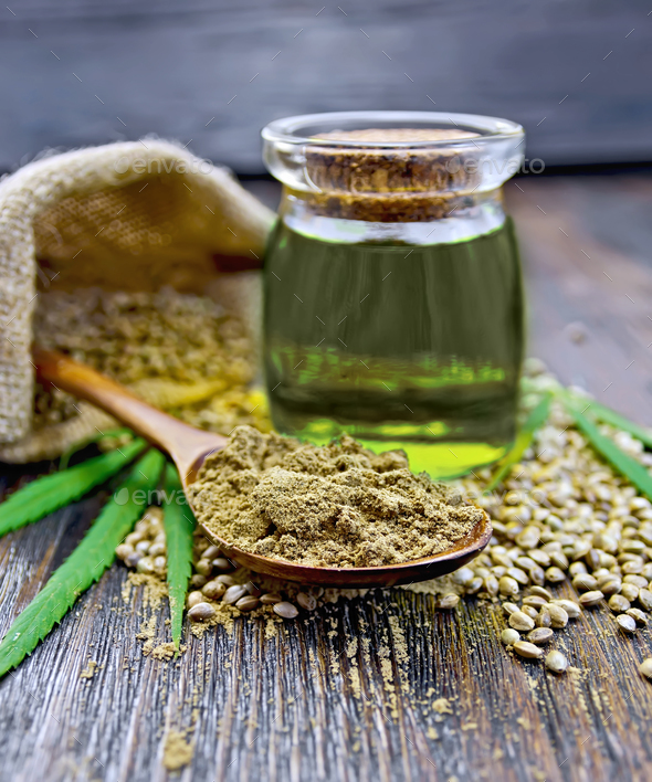 Flour hemp in spoon with oil and bag on dark board - Stock Photo - Images