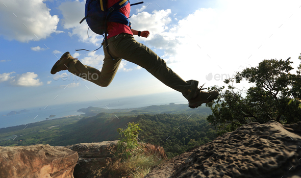 Jumping over precipice between two rocky mountains  - Stock Photo - Images