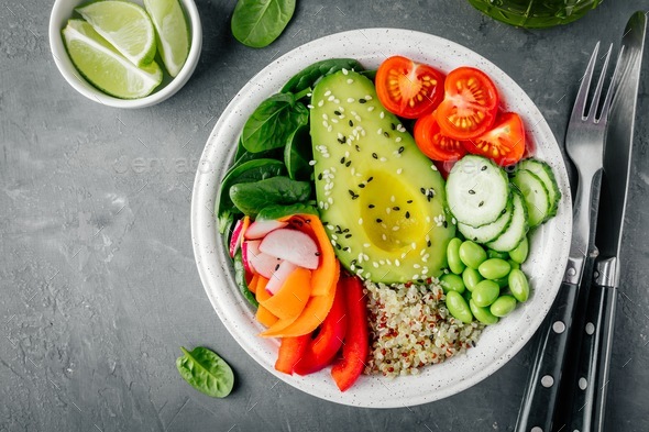 Buddha bowl. Avocado, quinoa, tomatoes, cucumbers, radishes, spinach, carrots, paprika and edamame. - Stock Photo - Images