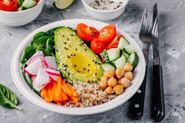 buddha bowl with quinoa, spinach, avocado, cucumbers, tomatoes, carrots, radishes, chickpeas - Stock Photo - Images