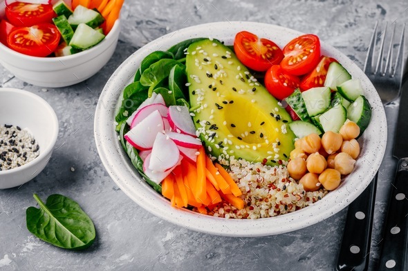 buddha bowl with quinoa, spinach, avocado, cucumbers, tomatoes, carrots, radishes, chickpeas - Stock Photo - Images