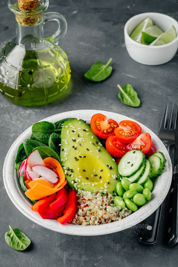 Buddha bowl. Avocado, quinoa, tomatoes, cucumbers, radishes, spinach, carrots, paprika and edamame. - Stock Photo - Images