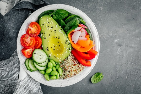 Healthy Buddha bowl. Avocado, quinoa, tomatoes, cucumbers, radishes, spinach, carrots and edamame - Stock Photo - Images