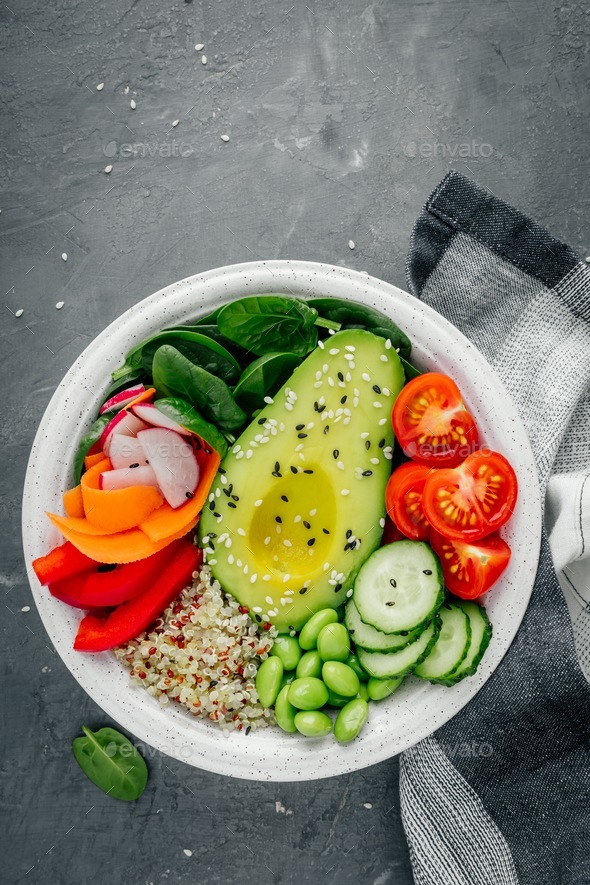 Buddha bowl. Avocado, quinoa, tomatoes, cucumbers, radishes, spinach, carrots, paprika and edamame. - Stock Photo - Images
