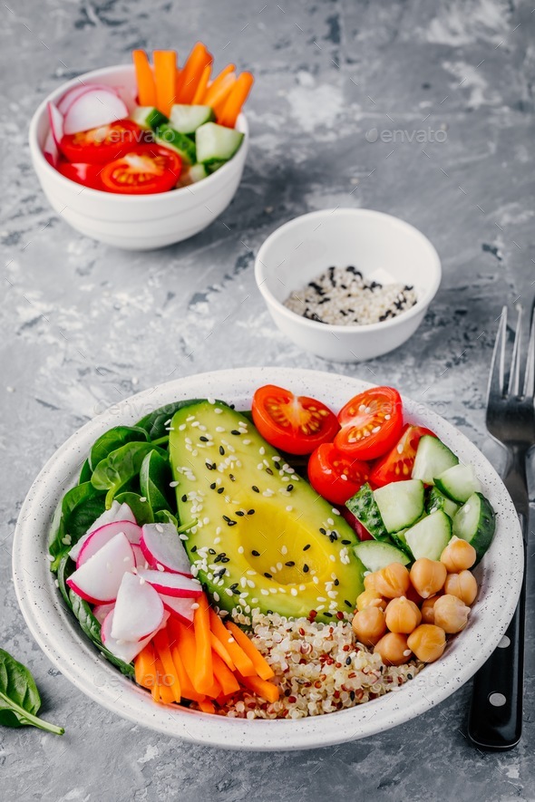 buddha bowl with quinoa, spinach, avocado, cucumbers, tomatoes, carrots, radishes, chickpeas - Stock Photo - Images