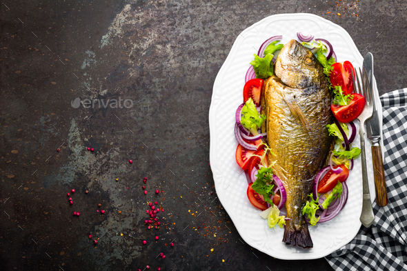 Baked fish dorado. Dorado fish oven baked and fresh vegetable salad on plate. Sea bream - Stock Photo - Images
