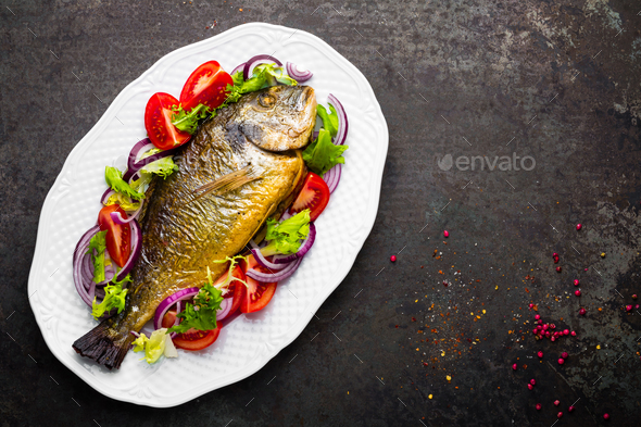 Baked fish dorado. Dorado fish oven baked and fresh vegetable salad on plate. Sea bream - Stock Photo - Images