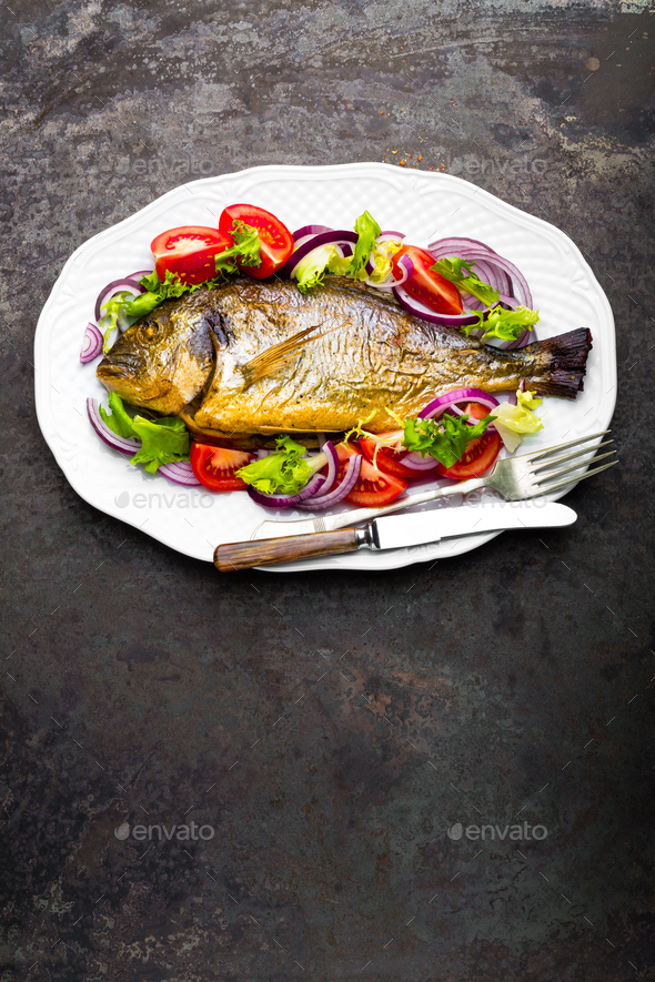 Baked fish dorado. Dorado fish oven baked and fresh vegetable salad on plate. Sea bream - Stock Photo - Images