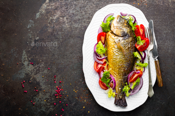 Baked fish dorado. Dorado fish oven baked and fresh vegetable salad on plate. Sea bream - Stock Photo - Images