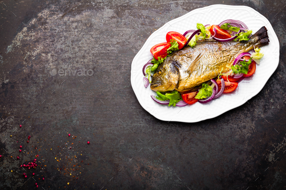 Baked fish dorado. Dorado fish oven baked and fresh vegetable salad on plate. Sea bream - Stock Photo - Images