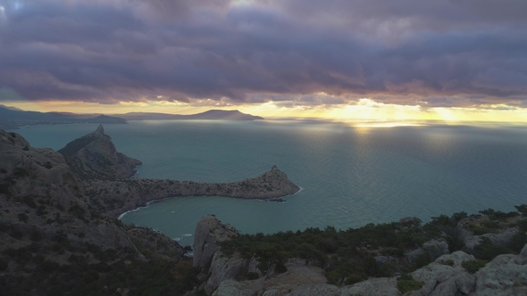 Drone Is Fast Backward Flying Over Climber Man Standing on Top of Rock at Sunrise. Aerial View alt