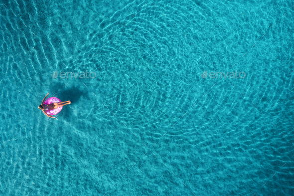 Aerial view of young woman swimming on the pink swim ring - Stock Photo - Images