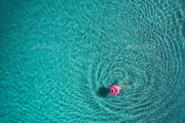 Aerial view of young woman swimming on the pink swim ring - Stock Photo - Images
