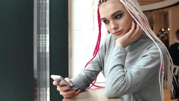 Teenager with Dreadlocks in a Coffee House. a Girl with an Unusual Appearance Uses a alt