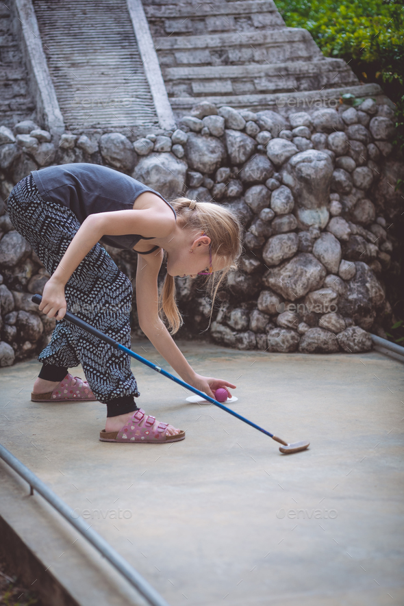 Happy little girl playing mini golf. - Stock Photo - Images