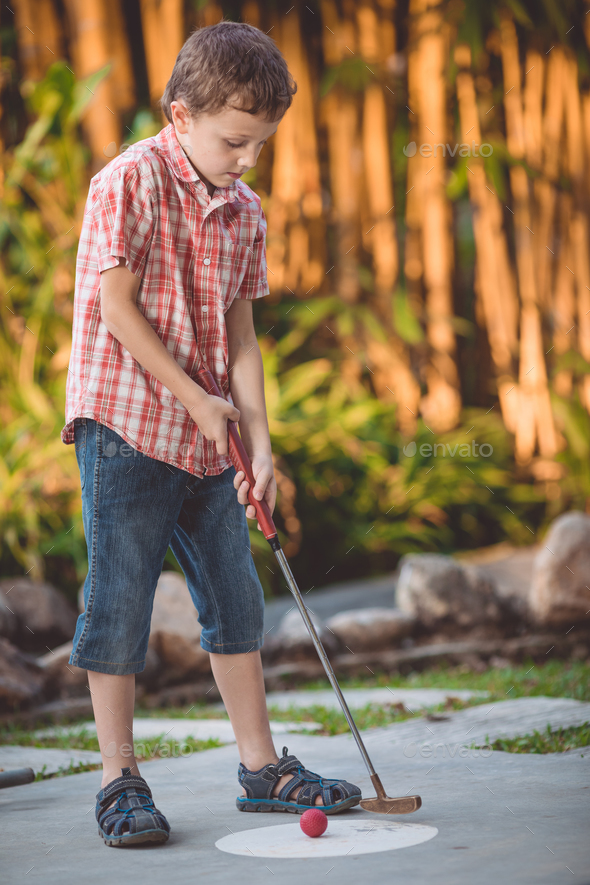 Happy little boy playing mini golf. - Stock Photo - Images